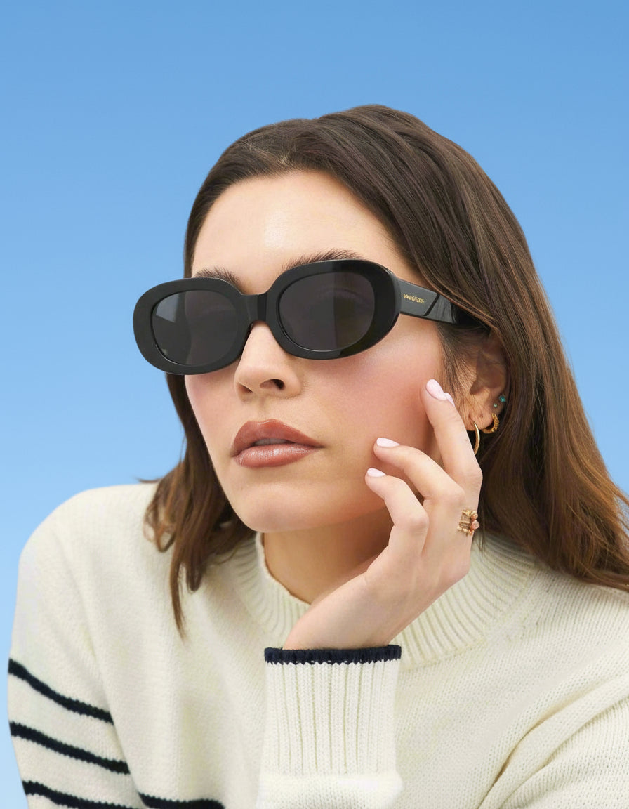Woman wearing black sunglasses against a blue background