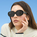 Woman wearing black sunglasses against a blue background