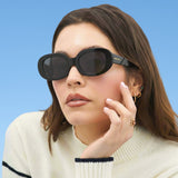 Woman wearing black sunglasses against a blue background